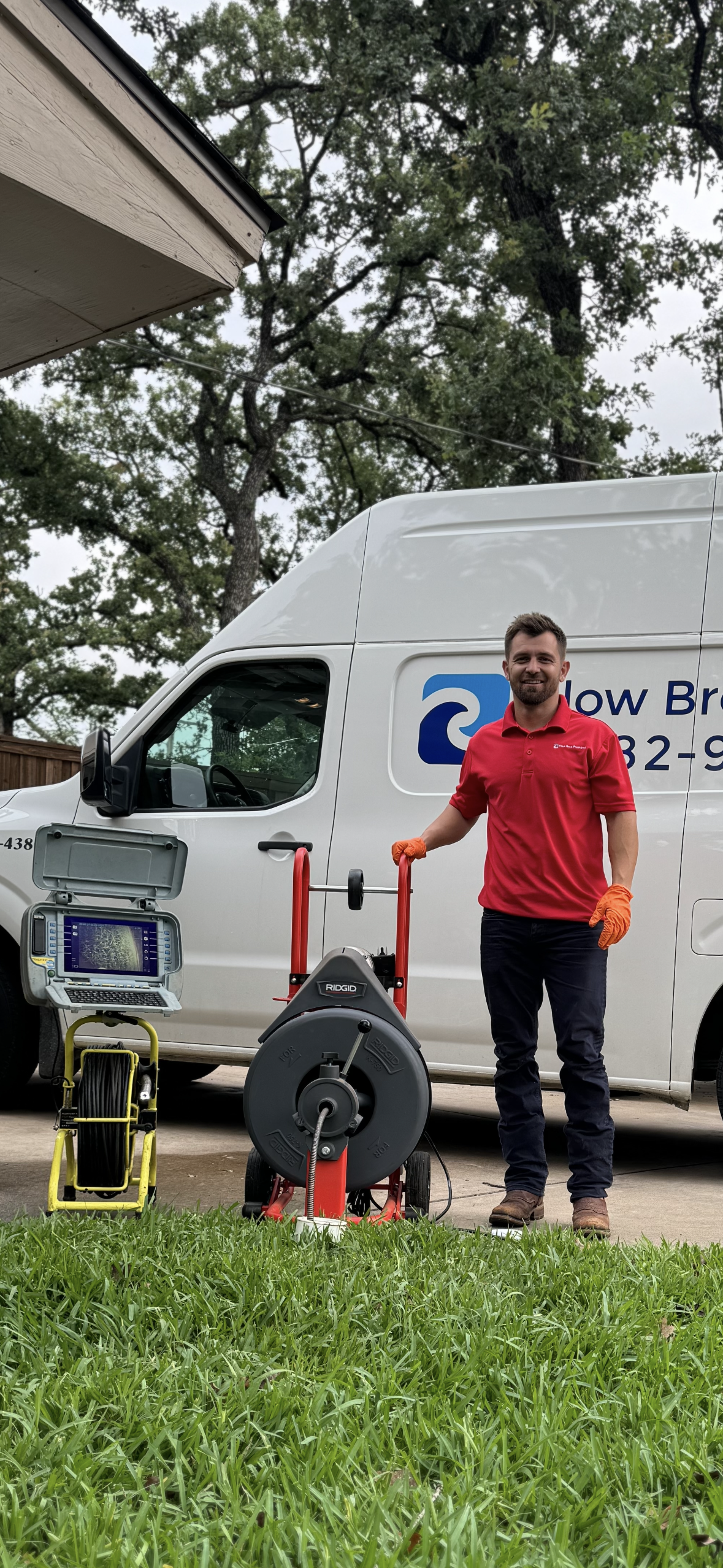 Flow Bros Plumbing technician with drain cleaning and sewer camera equipment beside a service van